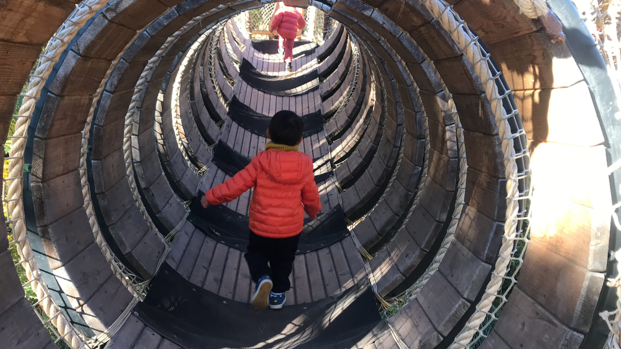 Kid in orange jacket walking through an elevated tunnel on Bronx Zoo Nature Trek